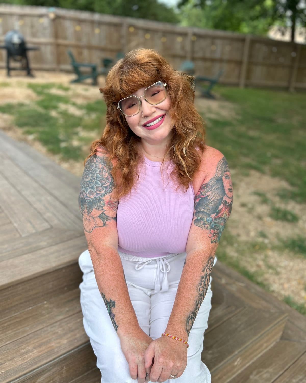 Kierstin Flores smiling, seated on wooden deck steps